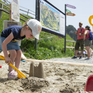 Une petite fille créant un château de sable au sommet des remontées mécaniques de Charmey