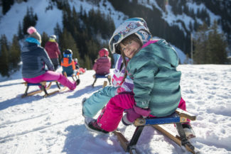 Deux enfants sur une luge au sommet des remontées mécaniques de Charmey