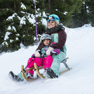 Une maman et sa fille dévalant la piste de luge à Charmey