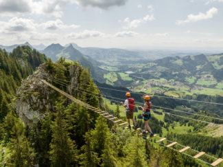 Deux personnes sur une passerelle suspendue faisant partie de la via ferrata de Charmey