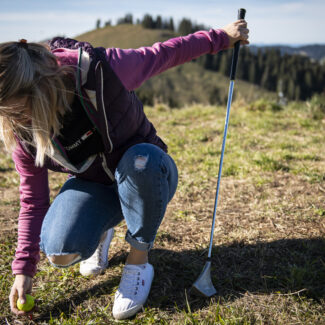 Une jeune femme ramasse sa balle de Swin golf sur le terrain de jeu de Charmey